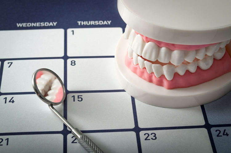 Dental model and mirror on a calendar representing a dental checkup schedule.
