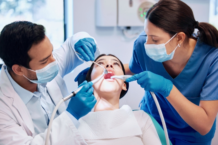 A dentist and dental assistant performing a wisdom teeth extraction on a patient in a dental clinic.